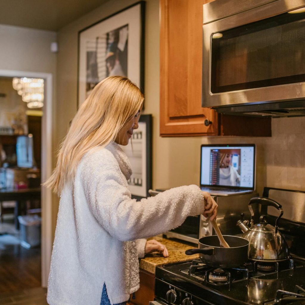 a-woman-cooks-while-attending-an-online-1364x1364