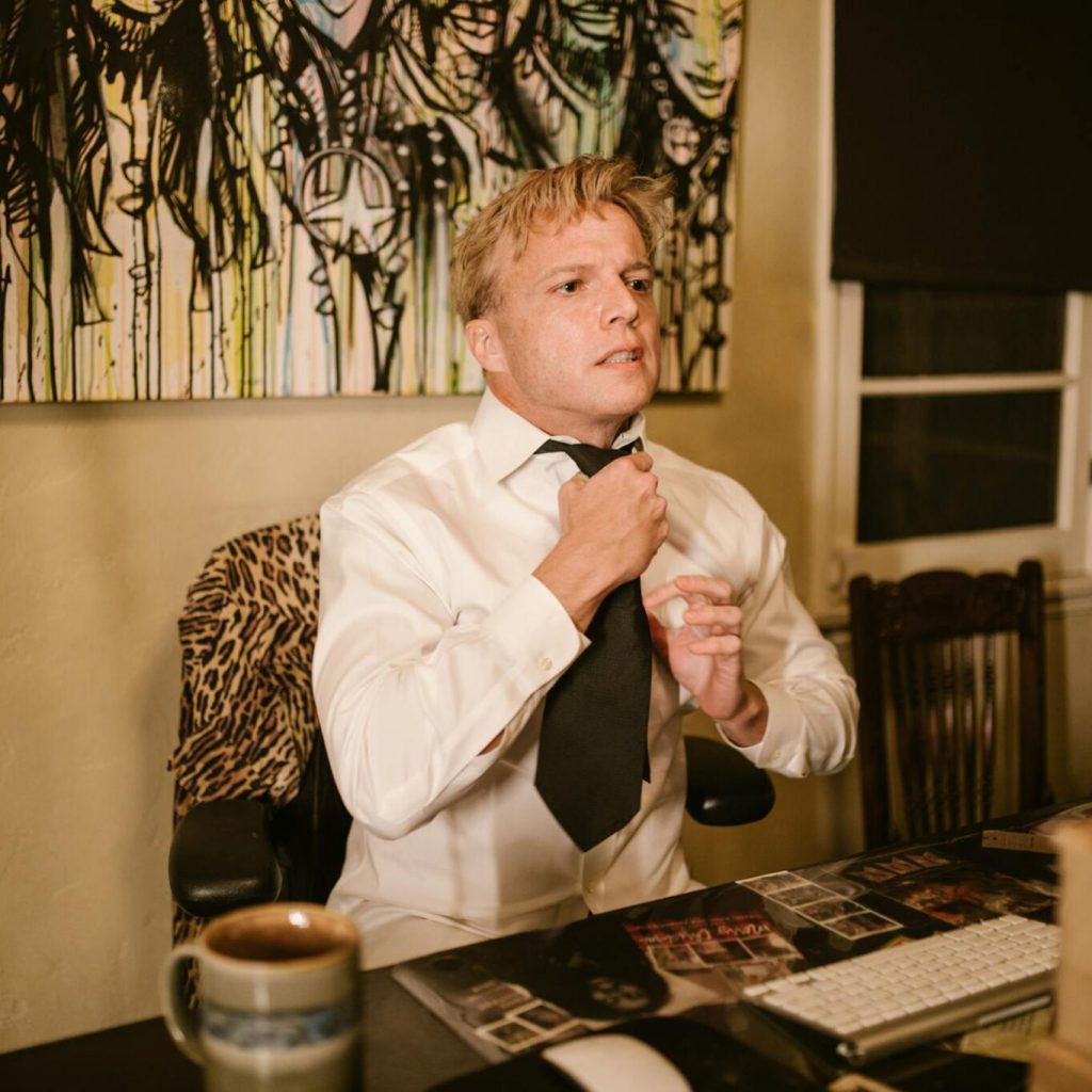 an-adult-man-adjusts-his-tie-in-a-home-office-ready-for-a-virtual-meeting-with-a-cup-of-coffee-on-the-desk.-6517291-2048x1365-1364x1364